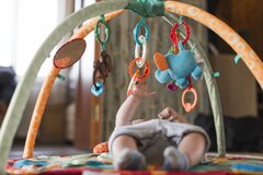baby-lying-developing-rug-with-mobile-educational-toys